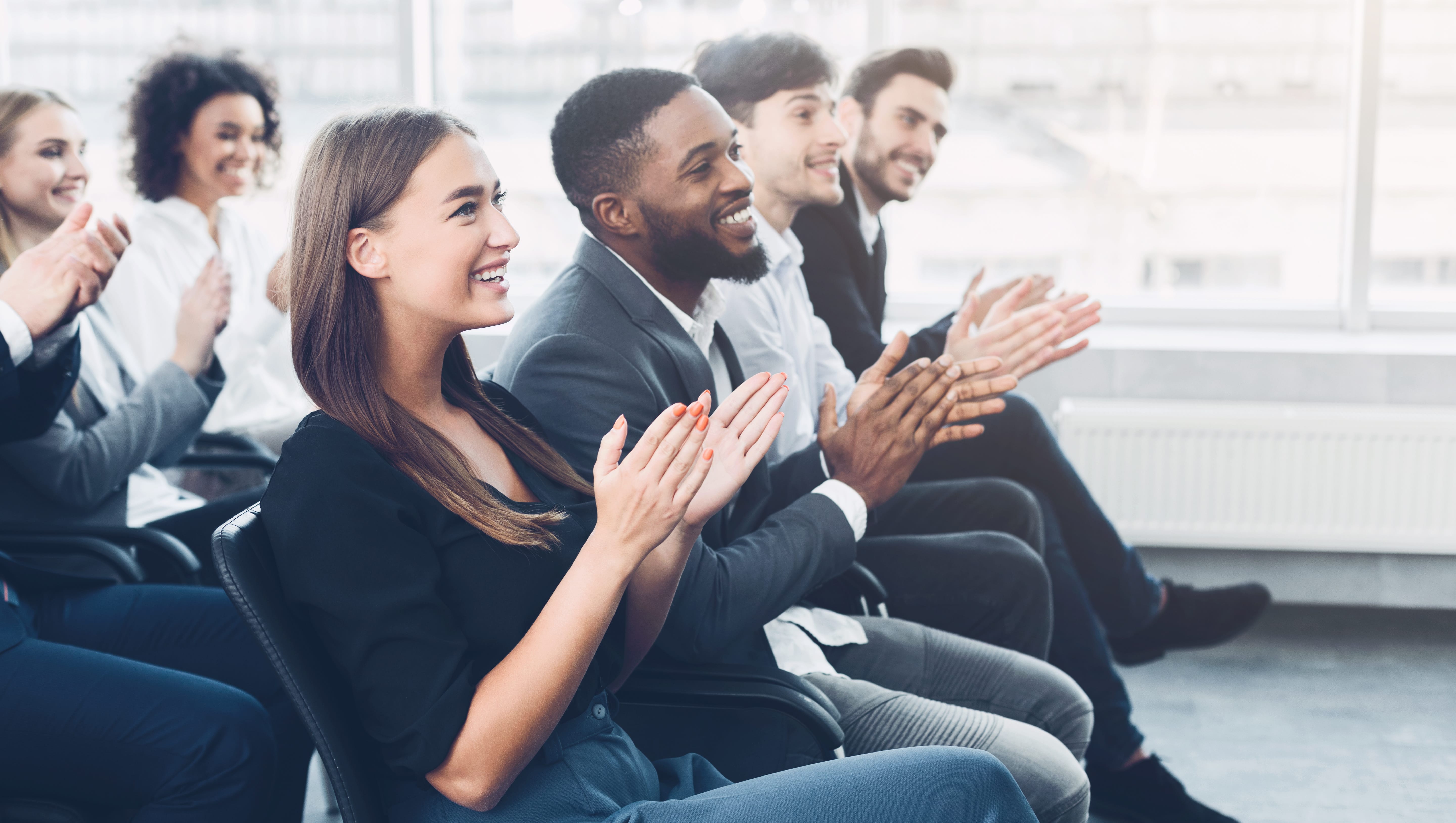 Young professionals sitting and clapping.